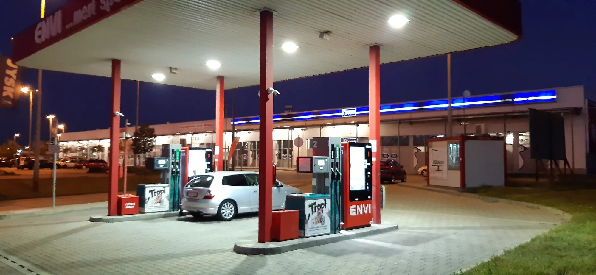 ENVI kút egy áruház parkolójában éjszaka, kivilágított tetővel