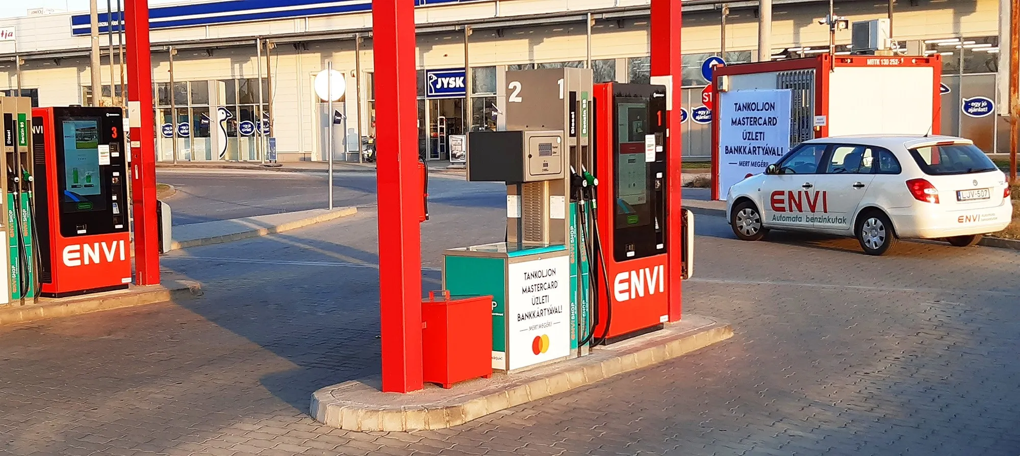 ENVI feliratos autó a kútoszlopok mellett egy áruház parkolójában