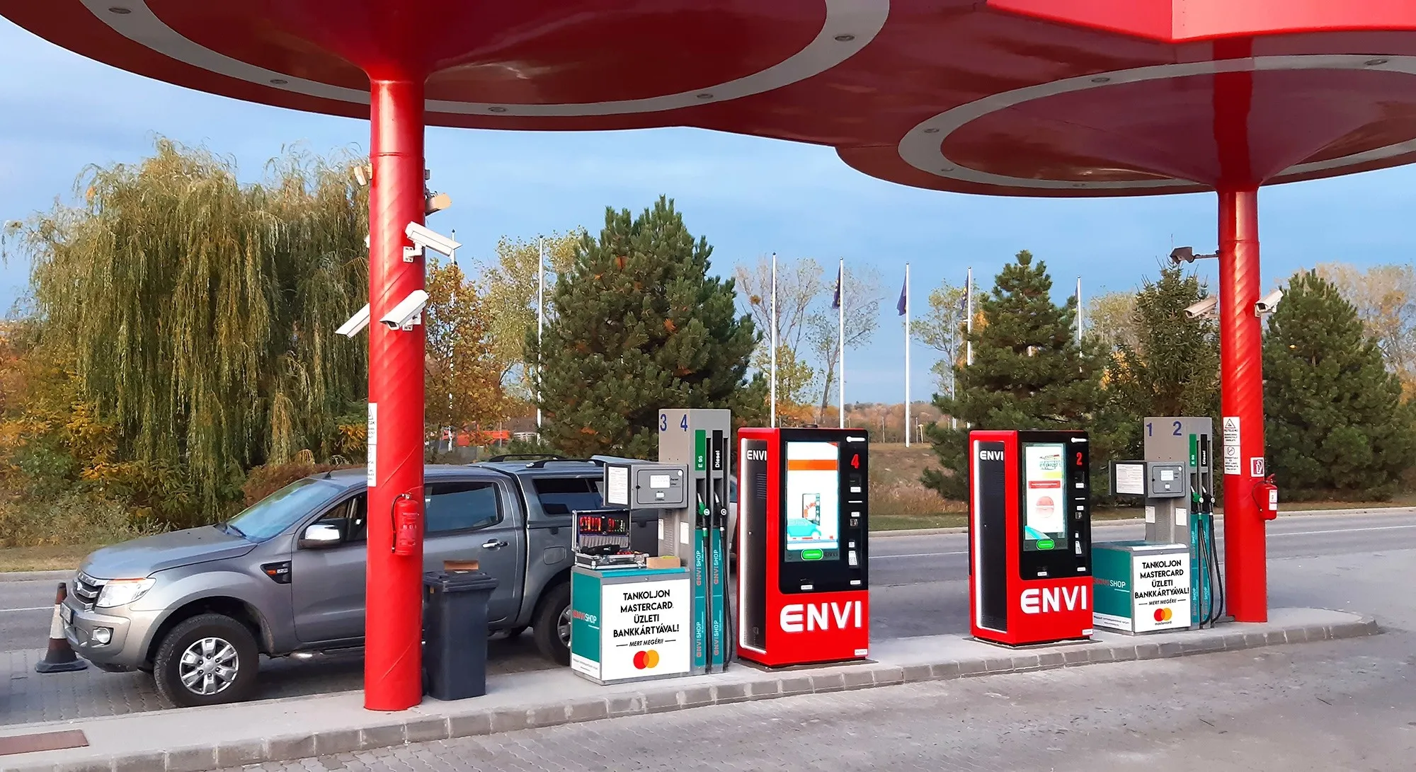 ENVI kútsor a piros, kerek lámpás tetőszerkezet alatt, egy pickup autóval